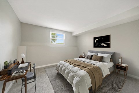 One-Bedroom Apartments in Marlborough, MA - Meadows at Marlborough - A Bedroom With Neutral Bedding, Desk Workspace, Soft Carpet, And Bright Window Lighting.