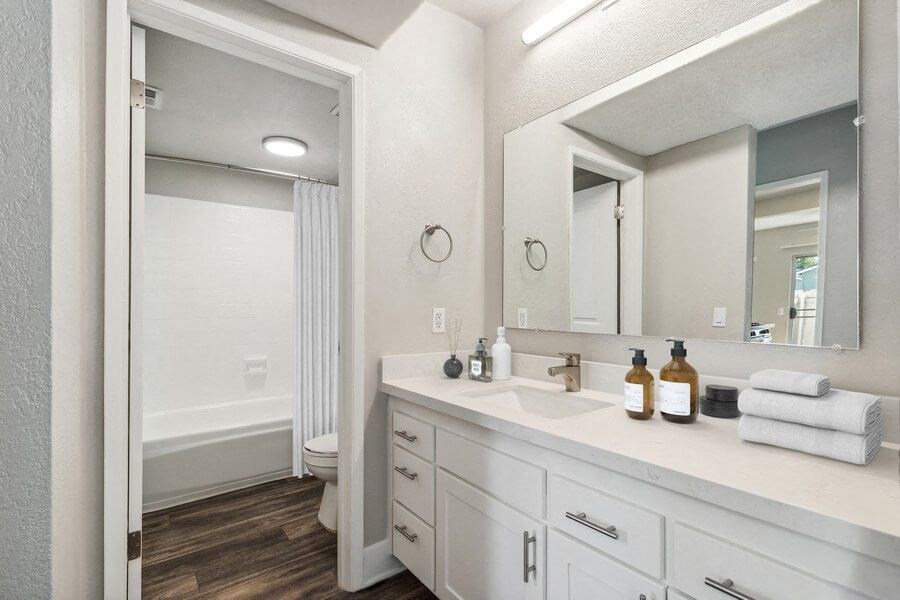 Model Bathroom 2 with Bathtub/Shower, Wood-Style Flooring & White Cabinets at Forest Park Apartments in El Cajon, CA.