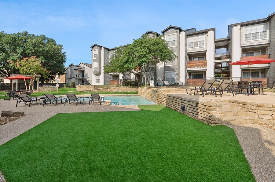 Community Swimming Pool with Pool Furniture and Turf Area at Cobblestone Apartments located in Arlington, TX.