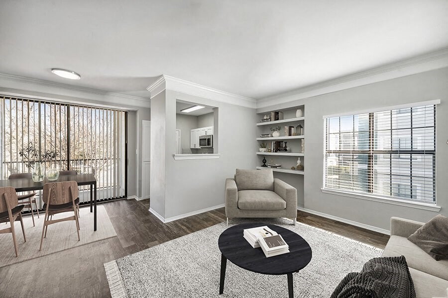 Model Living Room and Dining Room with Wood-Style Flooring and Patio Accessibility at Bridges at Oakbend Apartments located in Lewisville, TX.