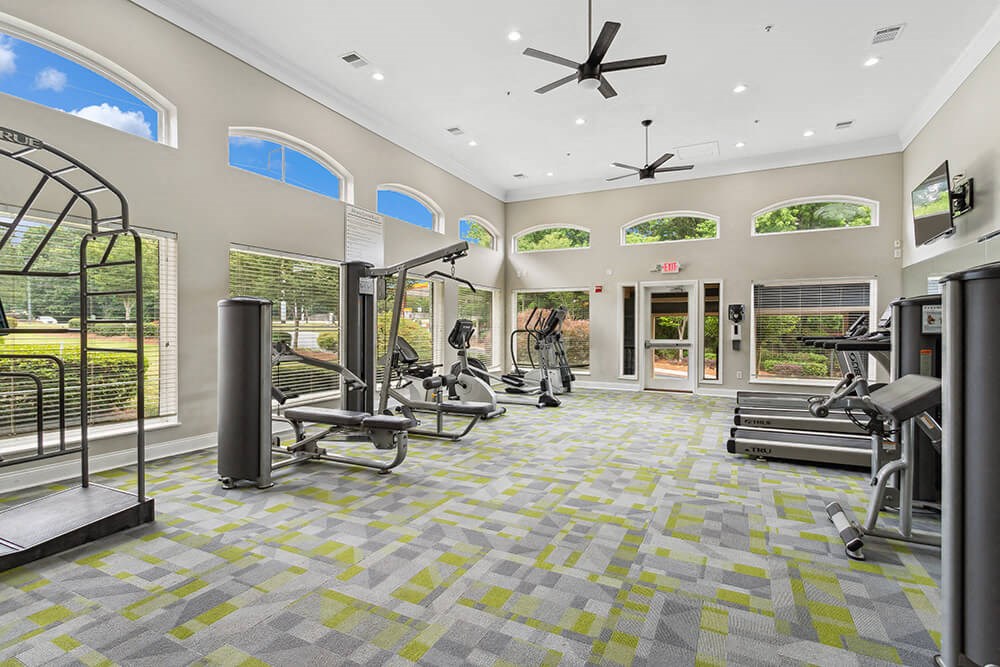 a spacious fitness center with exercise equipment and windows