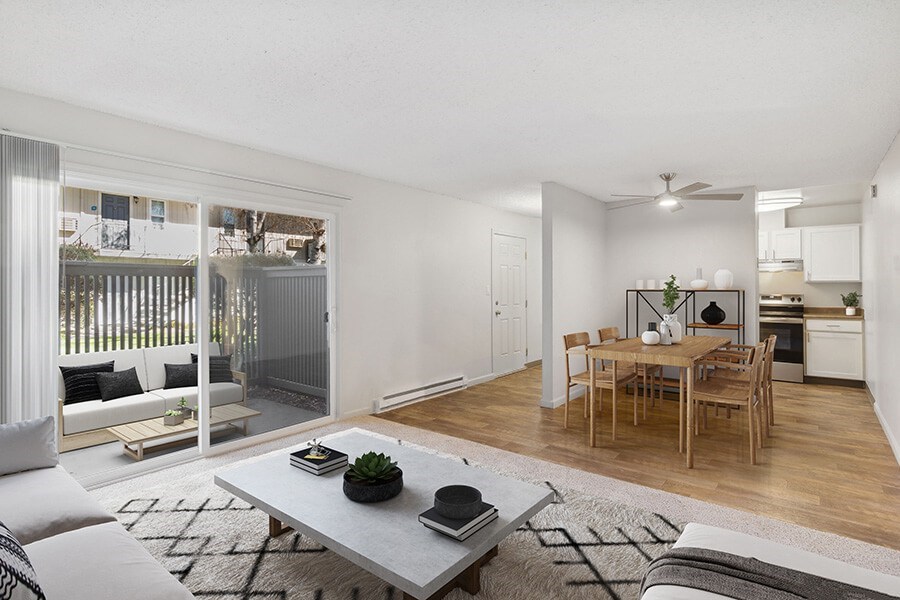 Model Living Room with Carpet, View of Dining Area, and Patio Accessibility at Los Gatos Landing Apartments located in San Jose, CA.