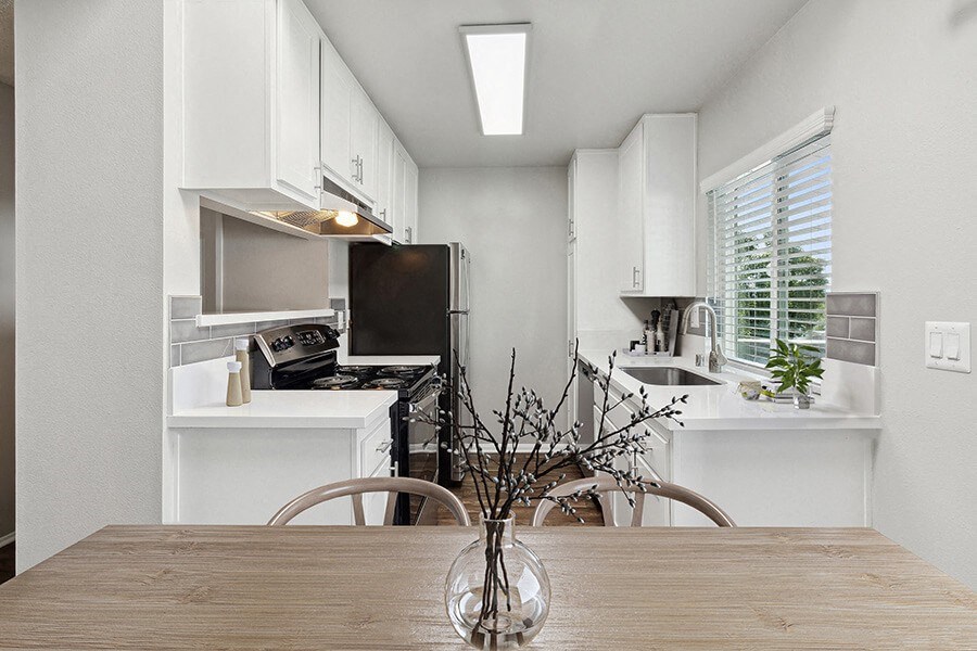 Model Kitchen with White Cabinets and Wood-Style Flooring at Colonnade at Fletcher Hills Apartments in El Cajon, CA.