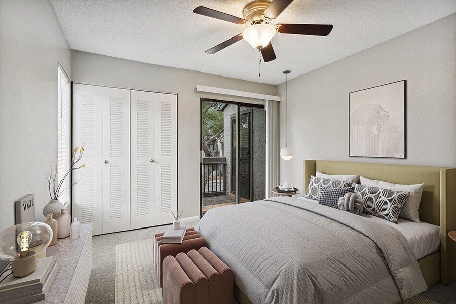 Model Bedroom with Carpet and Patio Accessibility at Huntington Place Apartments located in Sarasota, FL.