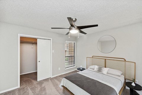 1 Bedroom Luxury Apartments in Far North Dallas, TX - Bridges at Deer Run - Bright Bedroom With Ceiling Fan, Plush Carpet, Window Blinds, And Open Closet Storage