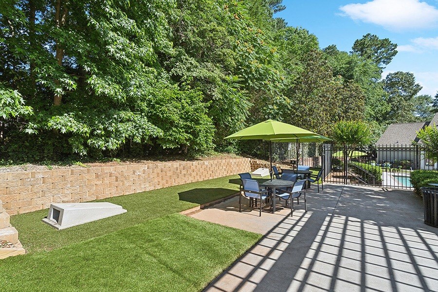 Outdoor Picnic Area with Lounge Furniture and Corn Hole Sets at Retreat at Stonecrest Apartments located in Lithonia, GA.