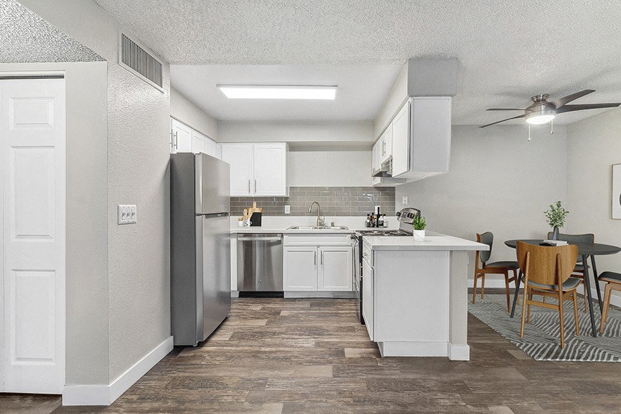 Model Kitchen with White Cabinets and Wood-Style Flooring with view of Dining Room at Meadow Ridge Apartments in Las Vegas, NV.