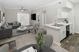 Model Dining Room and Kitchen Area with View of Living Room at Belmont at Duck Creek Apartments in Garland, TX.