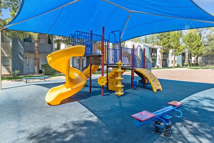 Community Playground with a Slide and Blue Canopy at Solano Springs Apartments in Tucson, AZ.