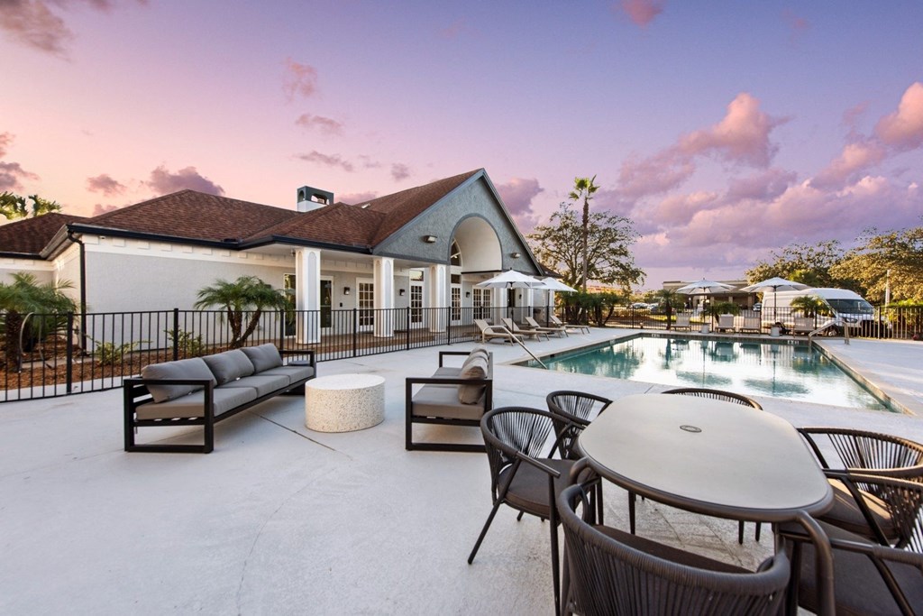a swimming pool with tables and chairs next to a building