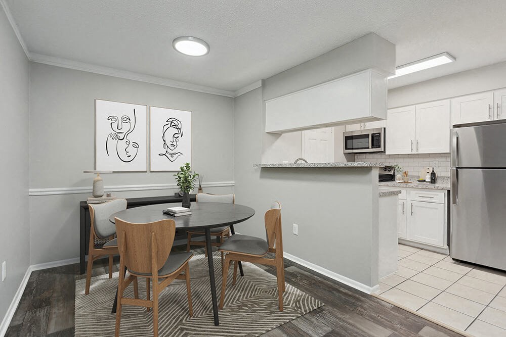 Model Dining Room with Wood-Style Flooring and View of Kitchen at Carrollwood Station Apartments in Tampa, FL.