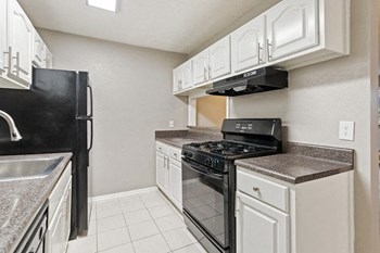 Model kitchen showcasing black appliances and tiled floor - Photo Gallery 6