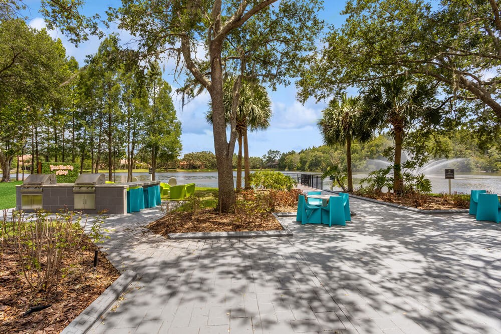 Pathway with tables and chairs on it with the lake  in the background
