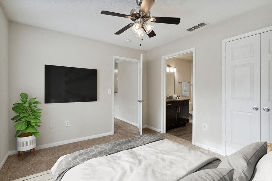 Model bedroom with ceiling fan and attached bath