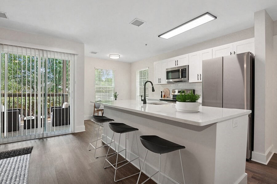 Model Kitchen with White Cabinets, Wood-Style Flooring and Patio Accessibility at Park at Caterina Apartments located in Charlotte, NC.