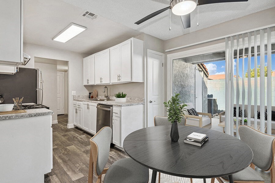 Model Dining Room with Wood-Style Flooring, View of Kitchen and Patio Accessibility at Peaks on 4th Apartments in Avondale, AZ.