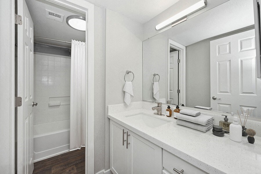 Model Bathroom with White Cabinets, Wood-Style Flooring and Shower/Tub at Crystal Creek Apartments located in Phoenix, AZ.
