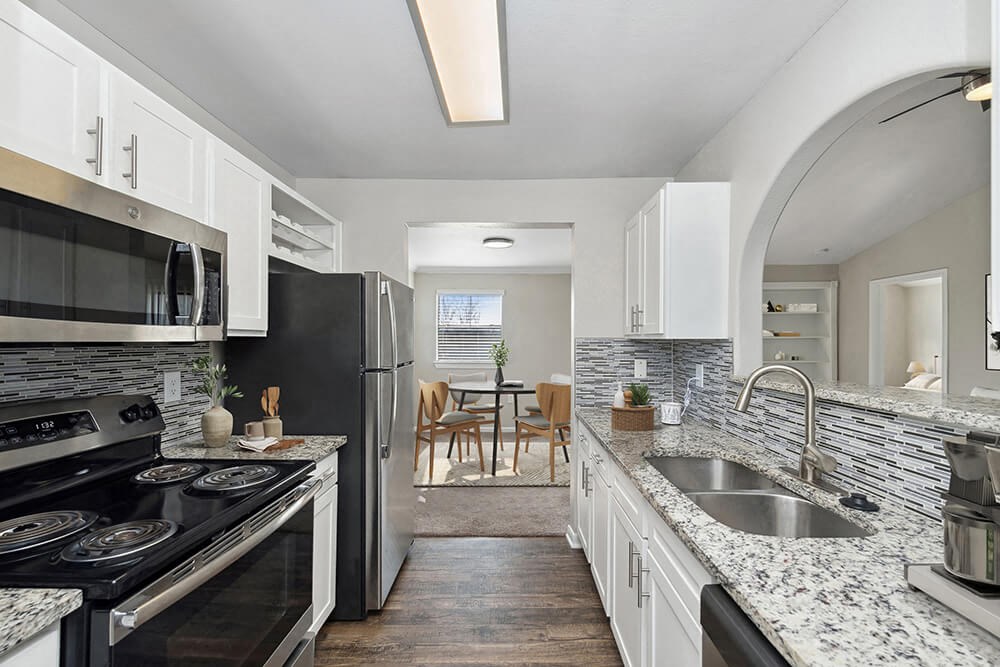 Model Kitchen with White Cabinets and Wood-Style Flooring at Hidden Creek Apartments in Lewisville, TX.