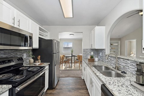 Model Kitchen with White Cabinets and Wood-Style Flooring at Hidden Creek Apartments in Lewisville, TX.