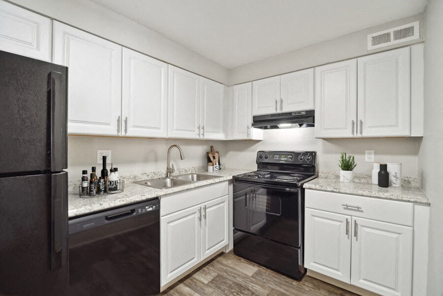 a kitchen with white cabinets and black appliances
