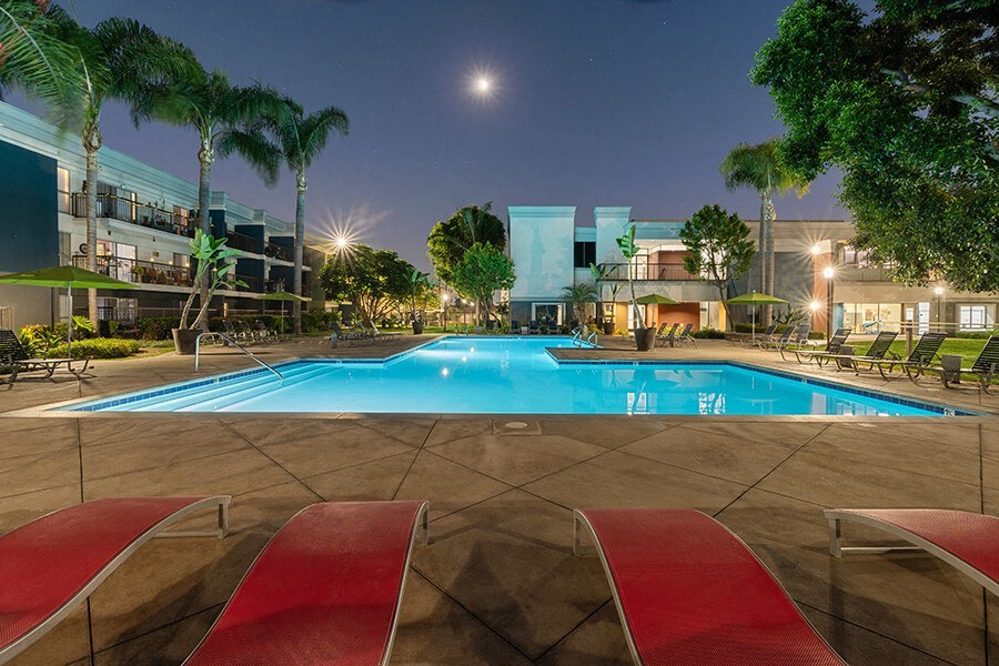 Community Swimming Pool with Pool Furniture at Madison Park Apartments located in Anaheim, CA.