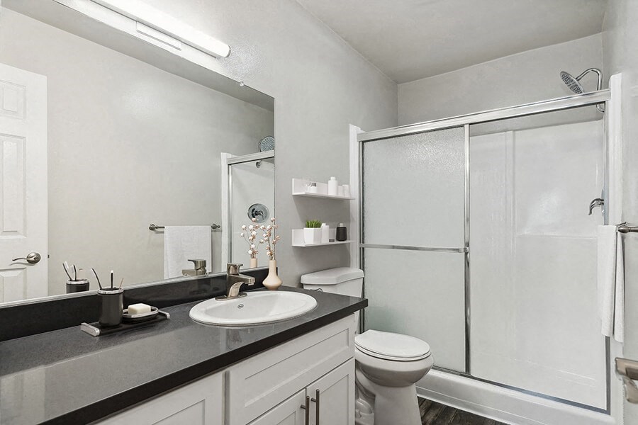 Model Bathroom with White Cabinets, Wood-Style Flooring and Shower at Madison Park Apartments located in Anaheim, CA.