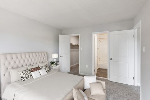 2-Bedroom Apartments in Woodbridge, VA - Brightwood Forest - A Bedroom With A Tufted Headboard Bed, Neutral Decor, And Carpeted Floors.