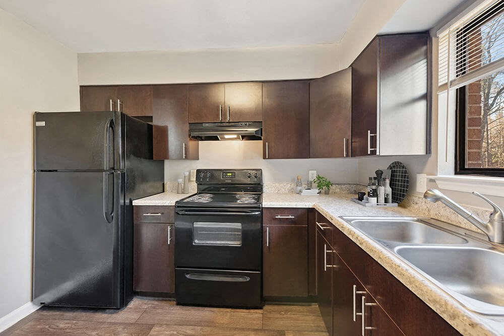 Model Kitchen with Brown Cabinets and Tile Flooring at Spring Forest Apartments in Raleigh, NC.