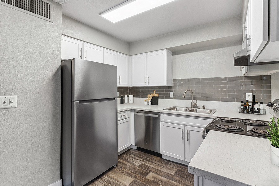 Model Kitchen with White Cabinets and Wood-Style Flooring at Meadow Ridge Apartments in Las Vegas, NV.