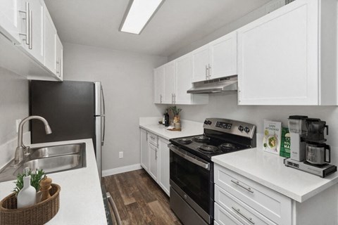a kitchen with white cabinets and black appliances and a sink