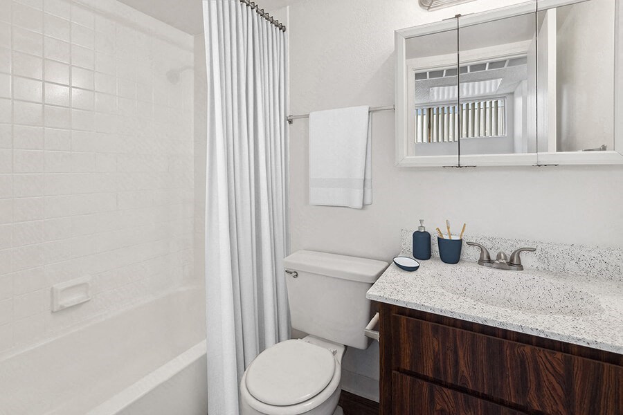 Model Bathroom with Dark Wood Cabinets, Wood-Style Flooring and Shower/Tub at Lakeside Casitas Apartments located in Tucson, AZ.