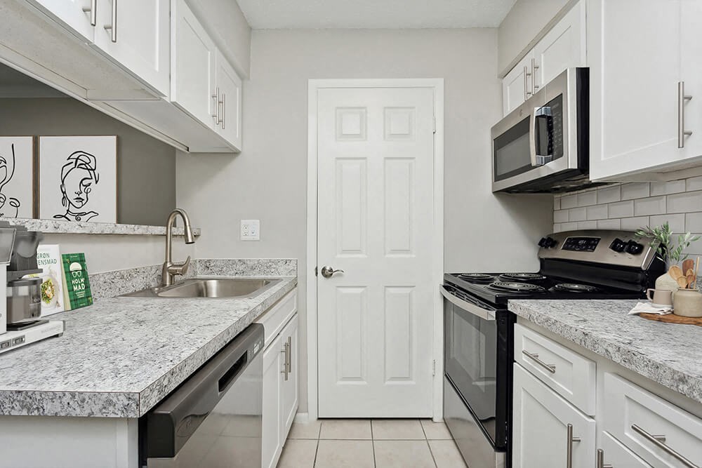 Model Kitchen with White Cabinets and Tile Flooring at Carrollwood Station Apartments in Tampa, FL.