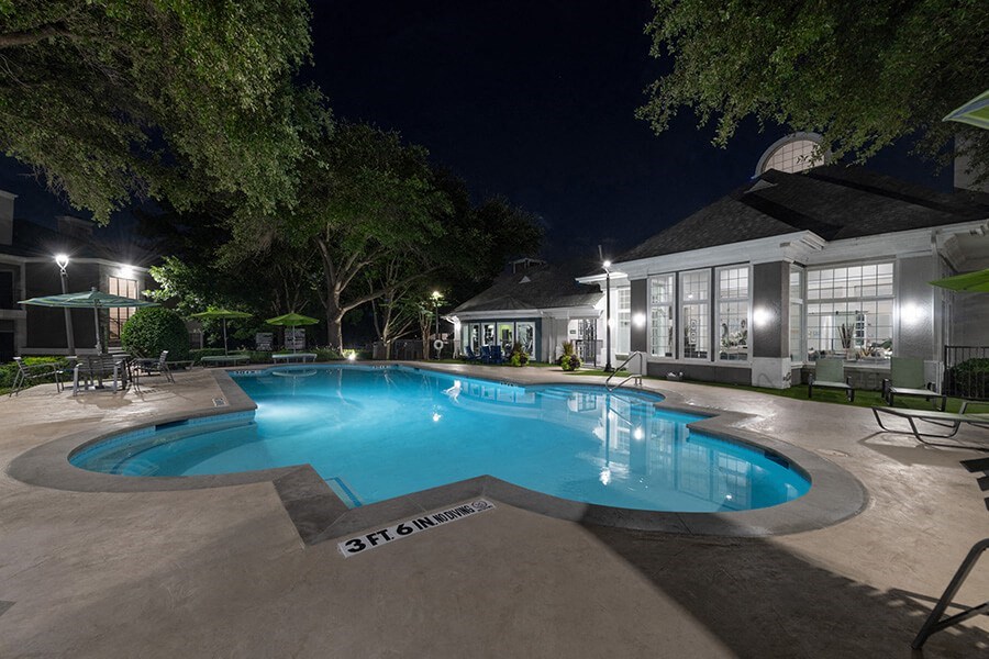 Community Swimming Pool with Pool Furniture at Bridges at Oakbend Apartments located in Lewisville, TX.