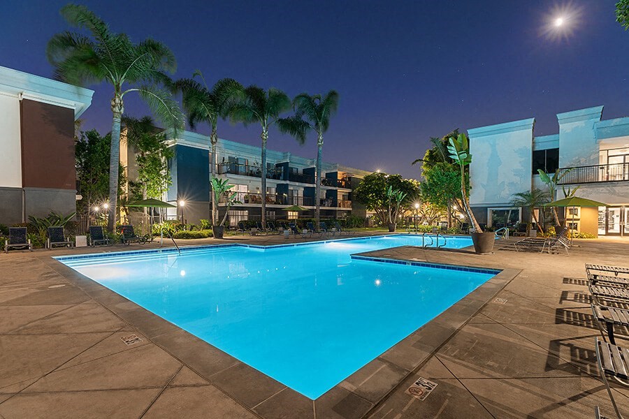 Community Swimming Pool with Pool Furniture at Madison Park Apartments located in Anaheim, CA.