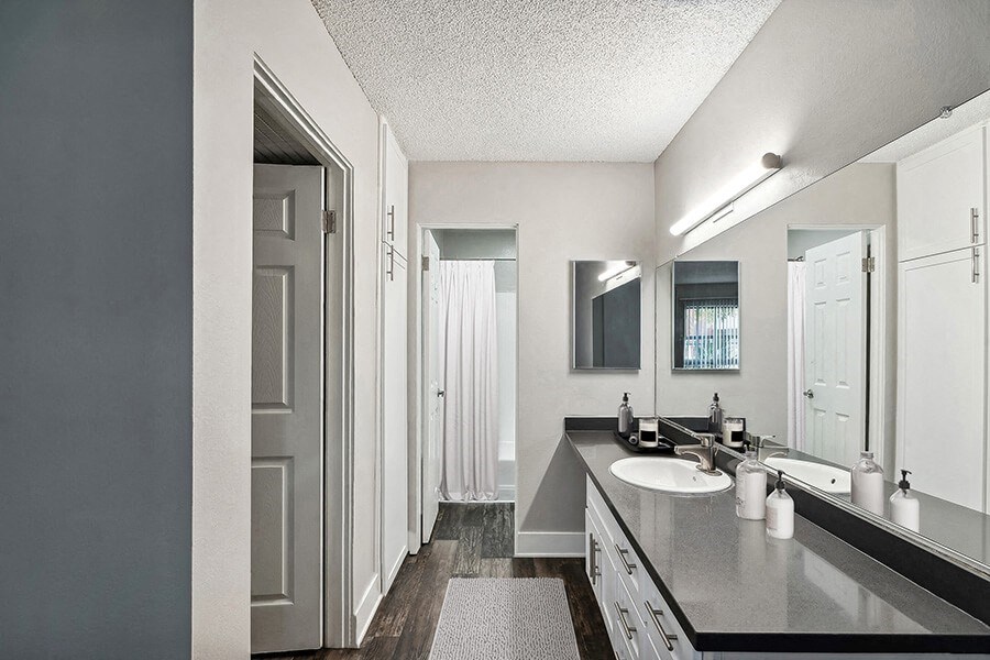 Model Bathroom with White Cabinets and Wood-Style Flooring at Madison Park Apartments located in Anaheim, CA.