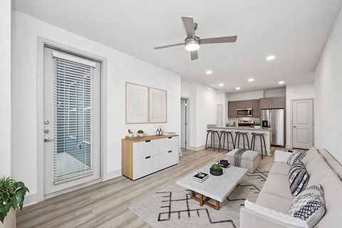Model Living Room with Wood-Style Flooring and View of Kitchen at Alta 3Eighty Apartments located in Aubrey, TX.