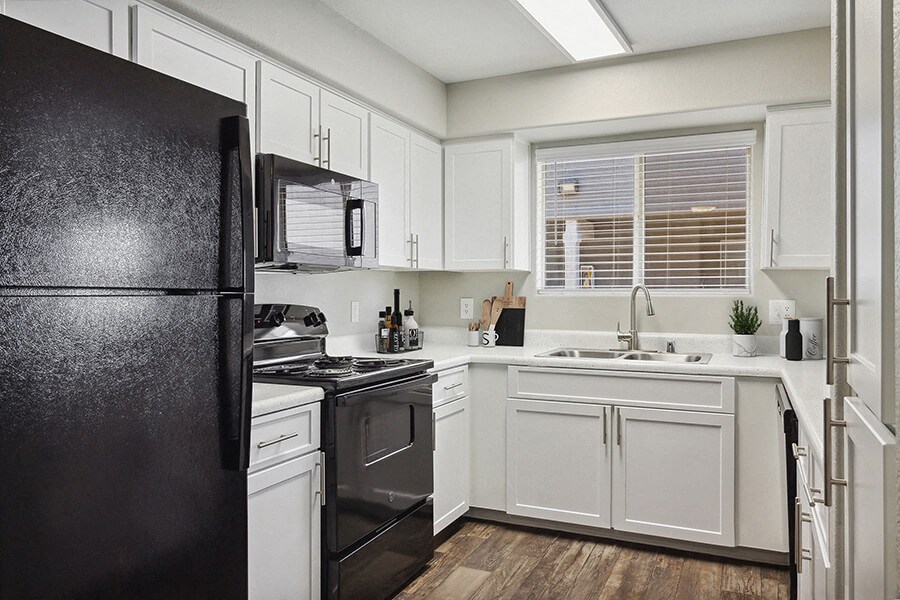 Model Kitchen with White Cabinets and Wood-Style Flooring at Verraso Apartments in Las Vegas, NV.