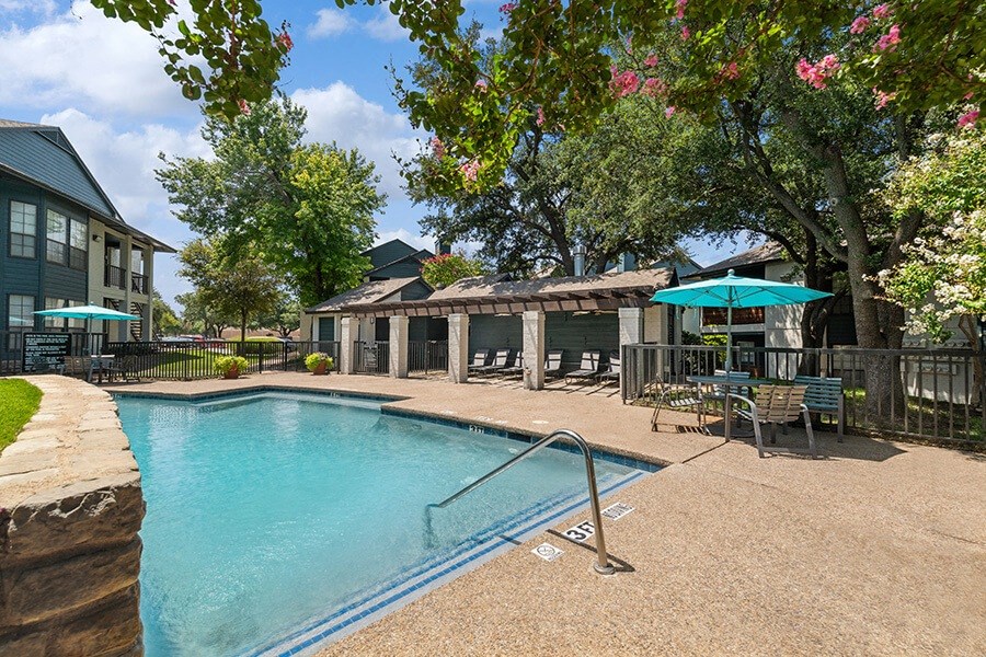 Community Swimming Pool with Pool Furniture at Bridges at Deer Run Apartments in Dallas, TX.