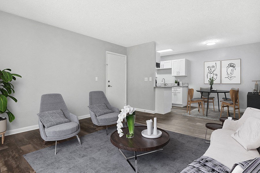 Model Living Room with Wood-Style Flooring and View of Kitchen/Dining Area at Stoney Trace Apartments in Charlotte, NC.