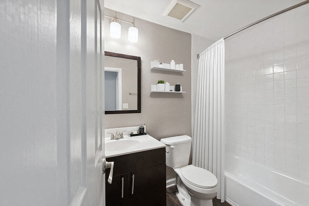 Model Bathroom with Dark Cabinets, Wood-Style Flooring and Shower/Tub at Spring Forest Apartments in Raleigh, NC.