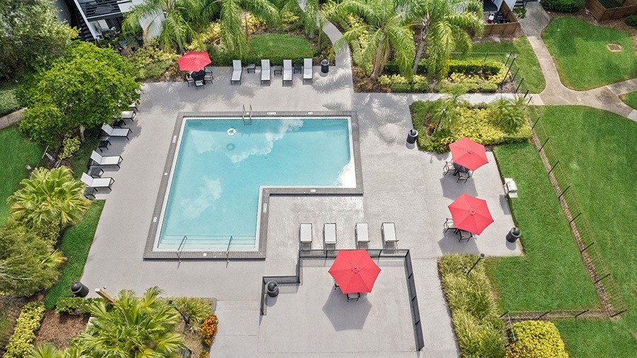 Aerial View of Community Swimming Pool and Pool Furniture at Rosehill Preserve Apartments in Orlando, FL.