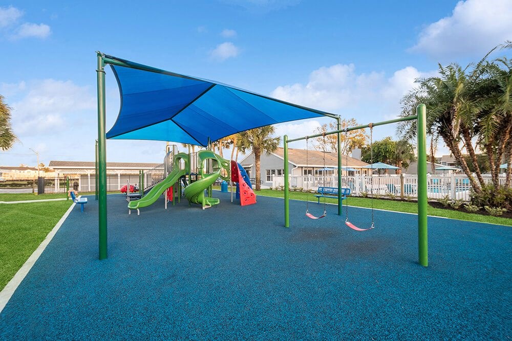 Community Playground with Slide, Swing Set and Blue Canopy at Park at 7200 Apartments in Jacksonville, FL.
