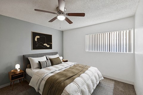 3-Bedroom Apartments in East Tucson, AZ - Lakeside Casitas - A Bedroom With A Neatly Made Bed, Bedside Tables, Ceiling Fan, Framed Wall Art, And A Window.