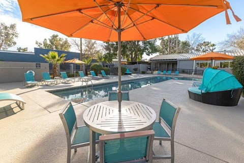 A table with an umbrella and chairs next to a pool  at Lakeside Casitas in Tucson, AZ