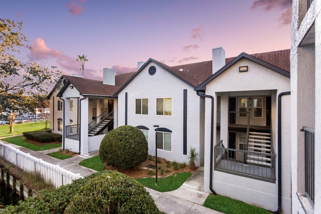 a group of white houses with a sidewalk and grass