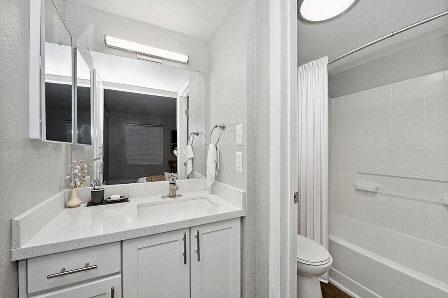 Model Bathroom with White Cabinets, Wood-Style Flooring and Shower/Tub at Crystal Creek Apartments located in Phoenix, AZ.