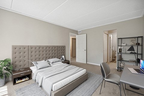 One-Bedroom Apartments in Burnsville, MN - Elevate on Parkway - A Bedroom With a Tufted Headboard, Neutral Carpet, Matching Nightstands, And Desk Workspace.
