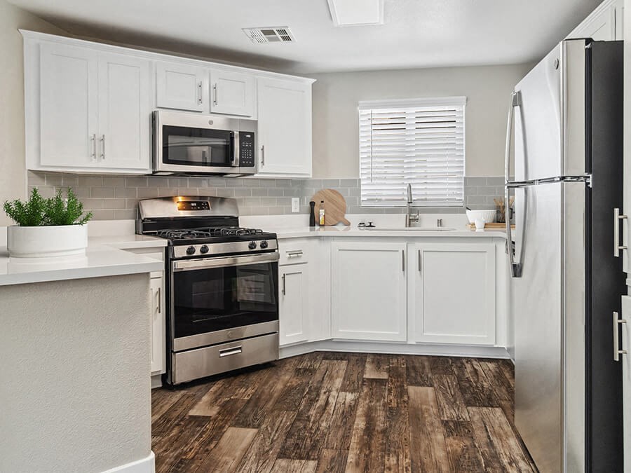 Model Kitchen with White Cabinets and Wood-Style Flooring at Reserve at Rancho Apartments located in Moreno Valley, CA.