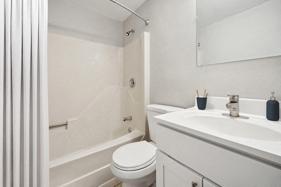 Model Bathroom with White Cabinets, Tile Flooring and Shower/Tub at Middlesex Crossing Apartments in Billerica, MA.