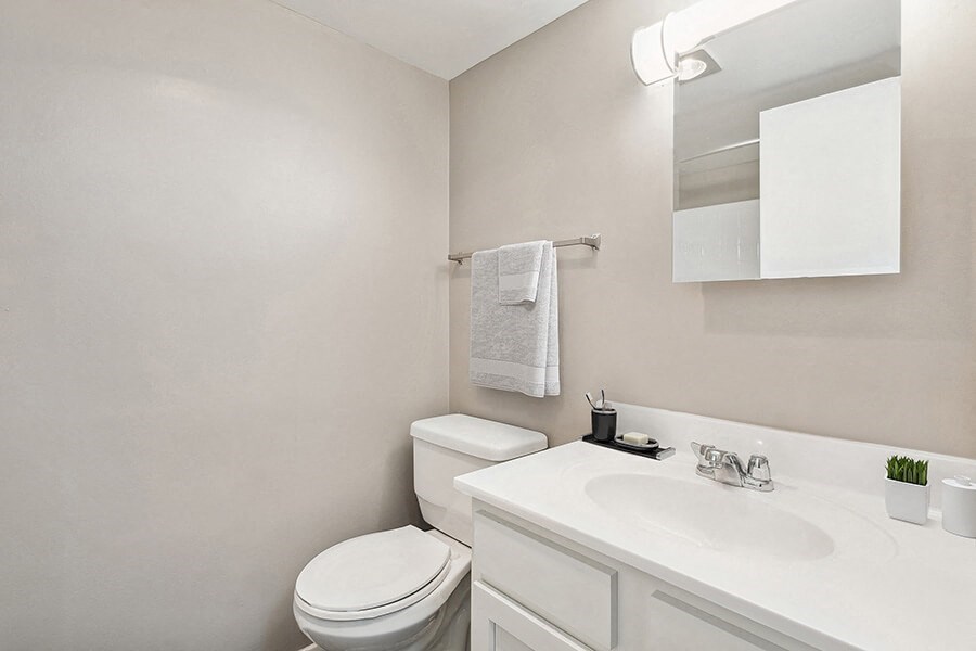 Model Bathroom with White Cabinets and Wood-Style Flooring at Spring Parc Apartments in Silver Spring, MD.